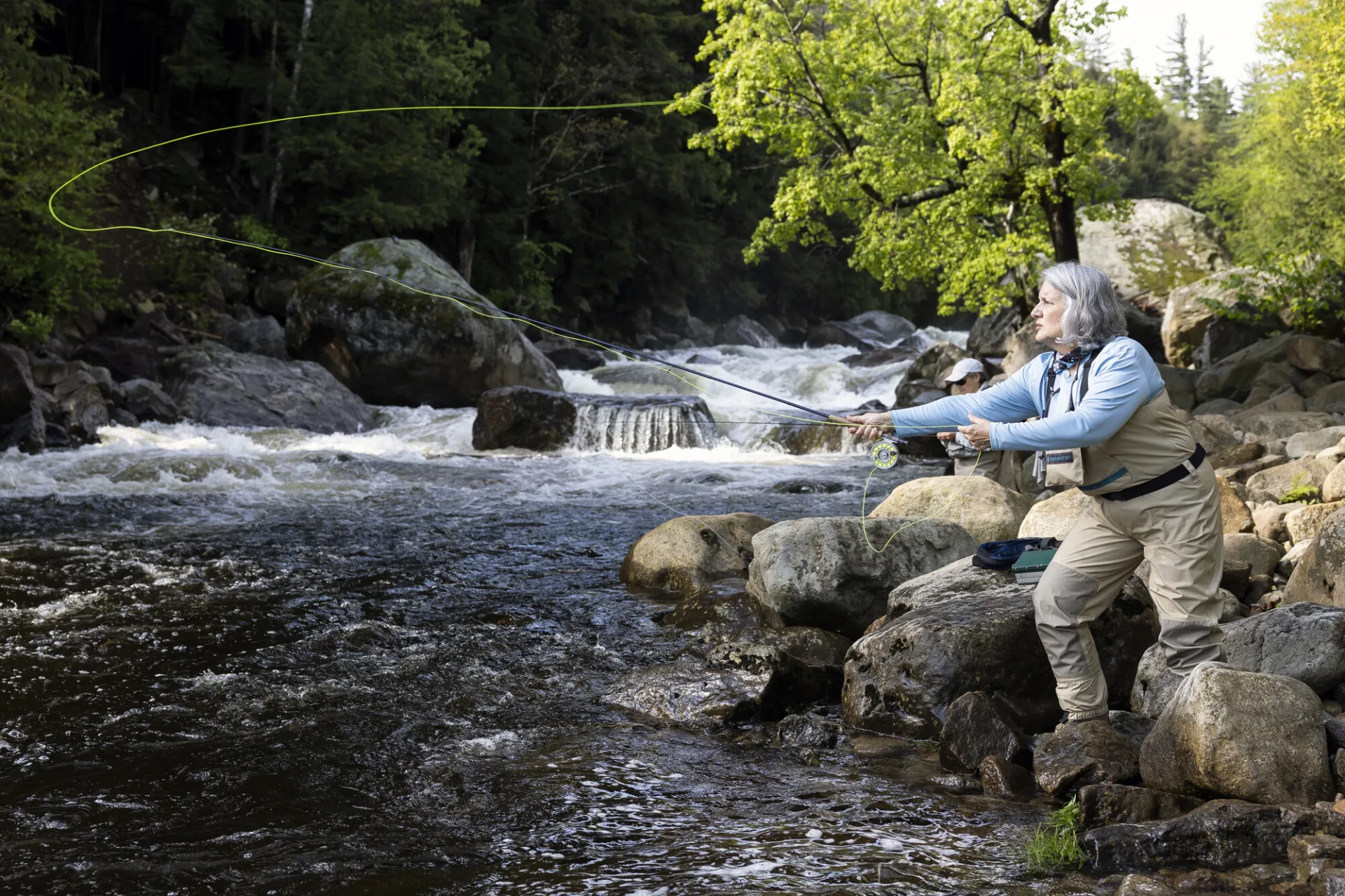 A fly fisher casting into a river