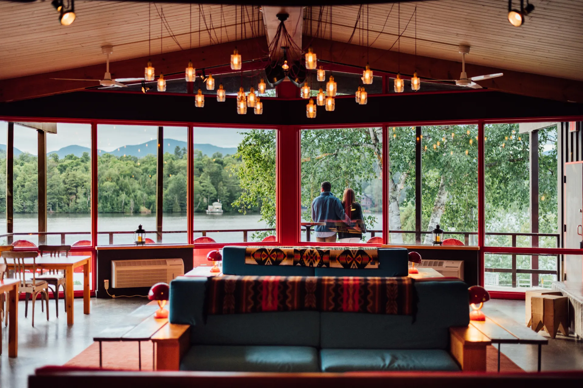 Large great room of Lake House with plaid patterned couches and small hanging lamps on ceiling