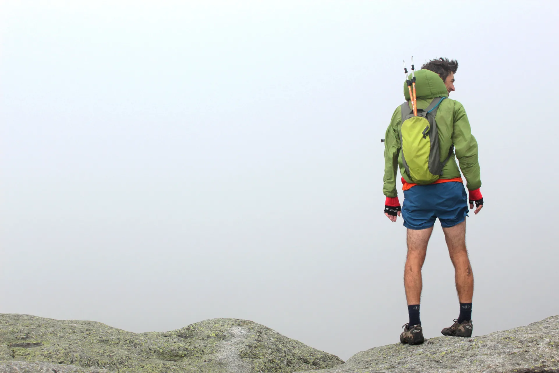A man stands on top of a rocky point.