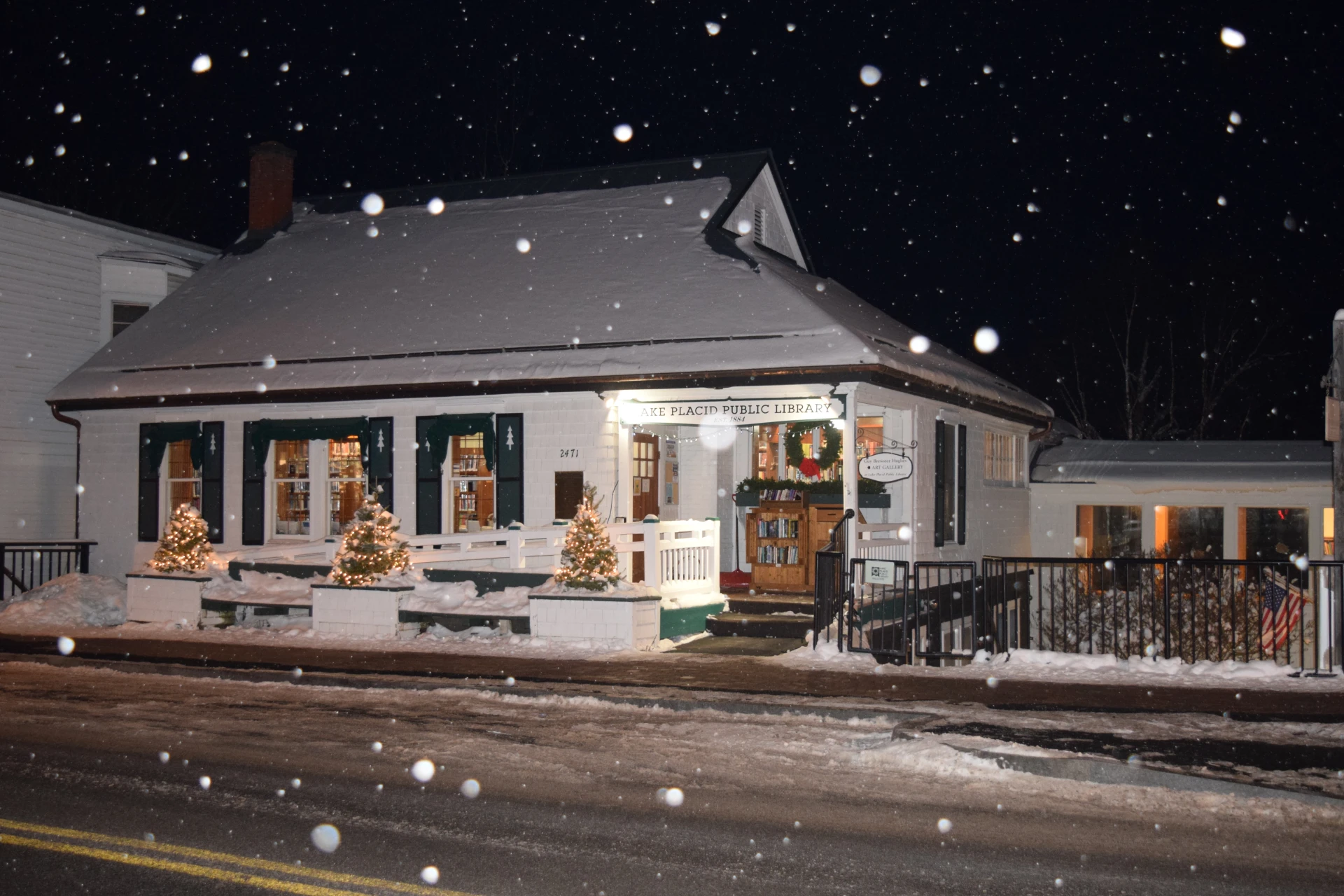 The Lake Placid Public Library at night with snow falling.