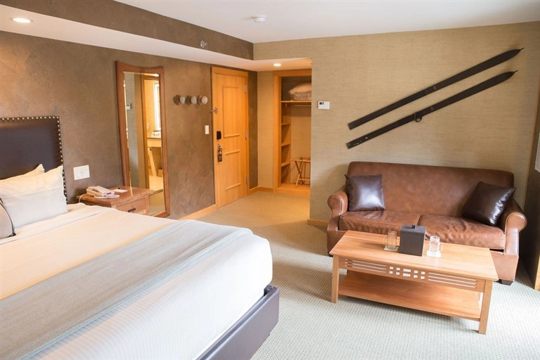A large room with fresh sheets, sitting area and warm lighting.