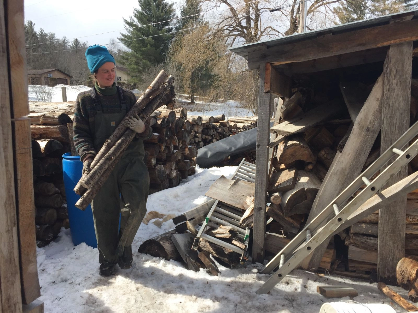 Lizzie, one of two assistants, is carrying wood for the wood fire stove beneath the evaporator.