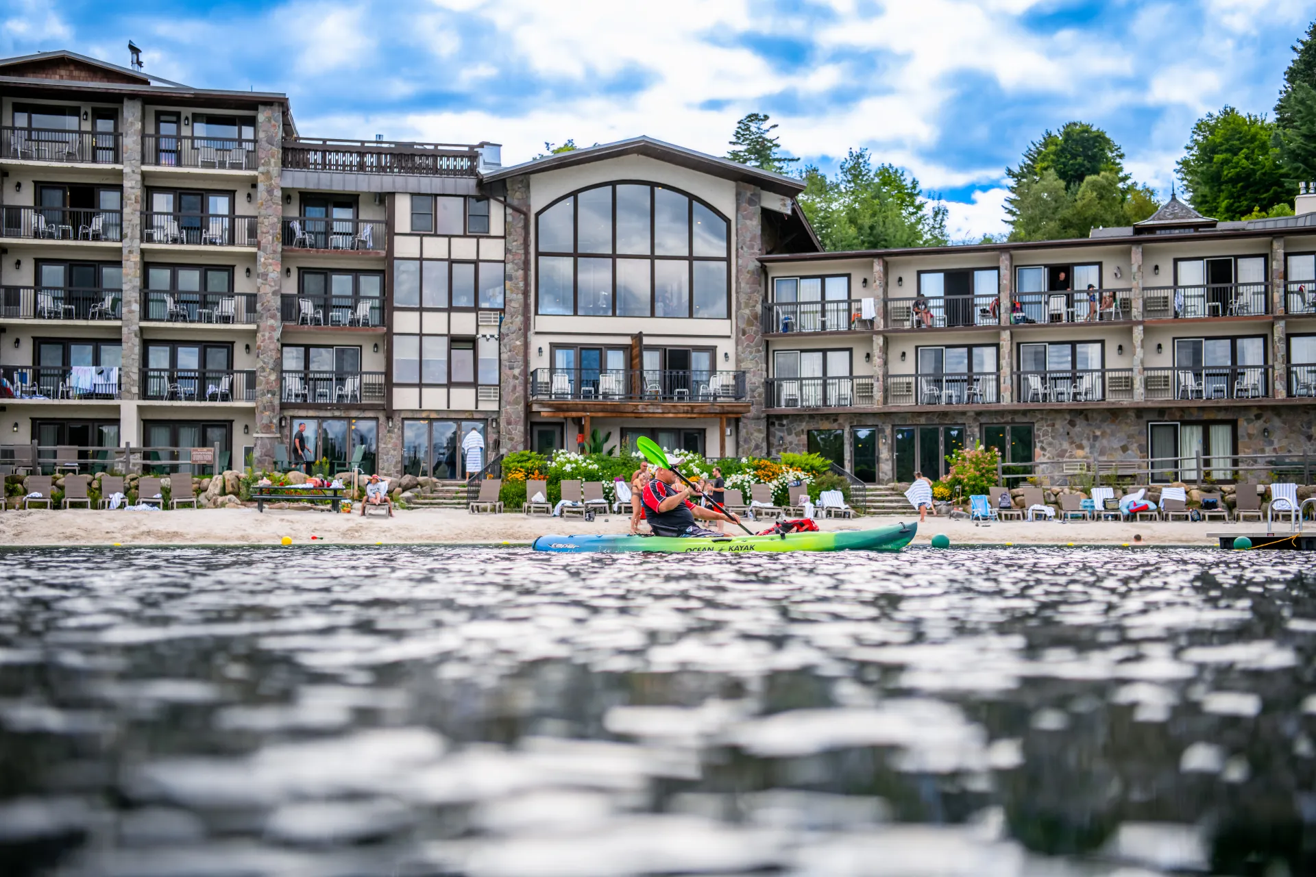 View of Golden Arrow Lakeside Resort with a kayaker paddling by from Mirror Lake.