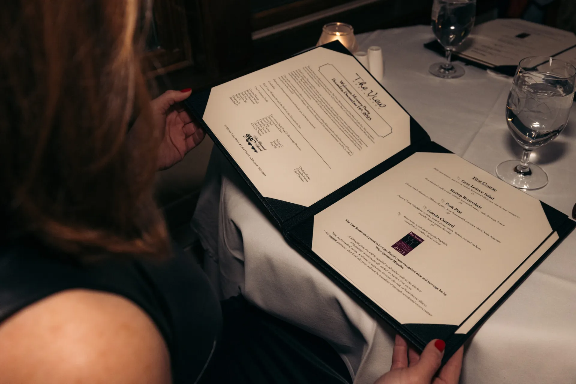 A woman looks over a menu at a high end restaurant. 