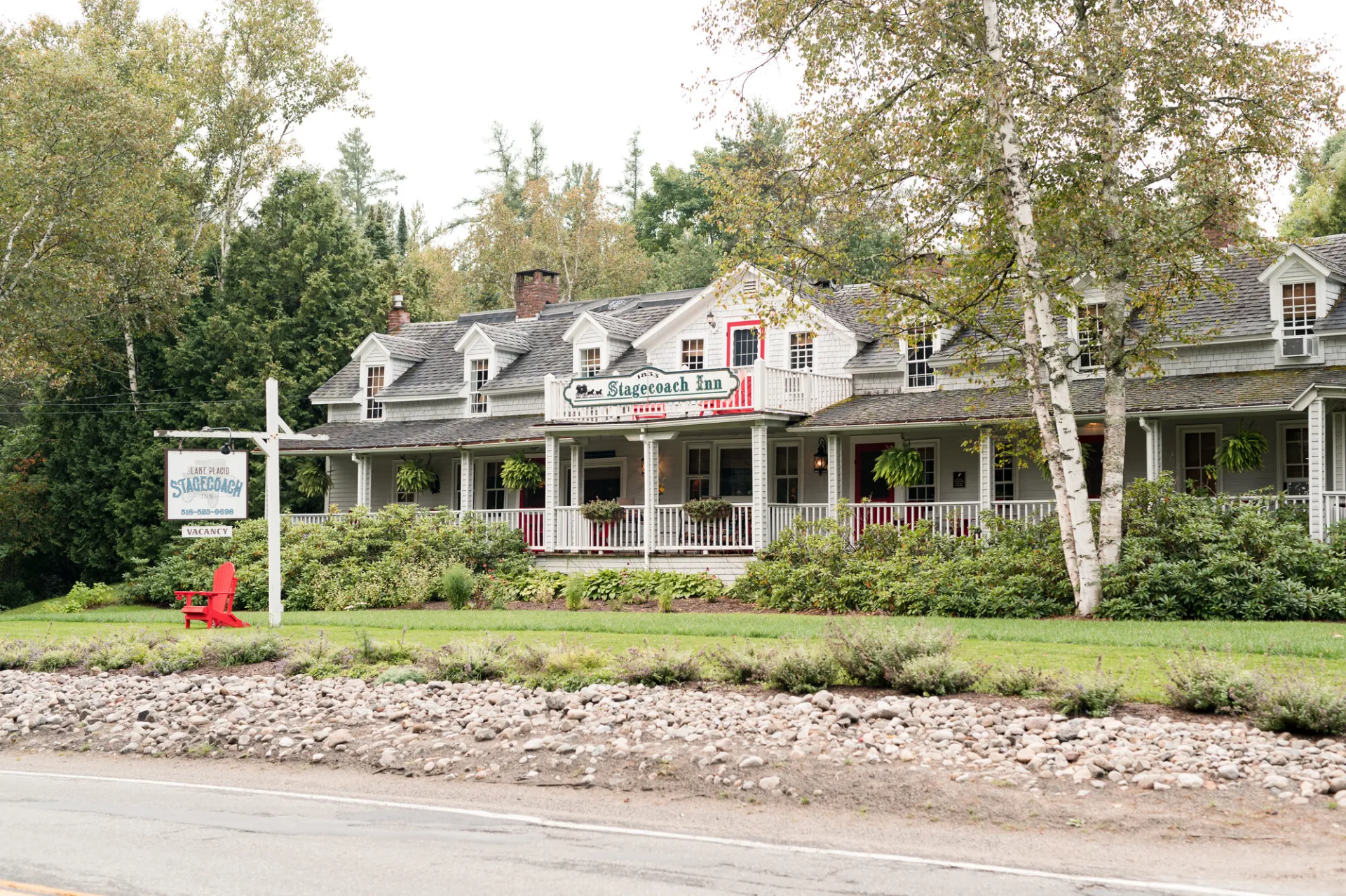 An white inn surrounded by an immaculate lawn. 