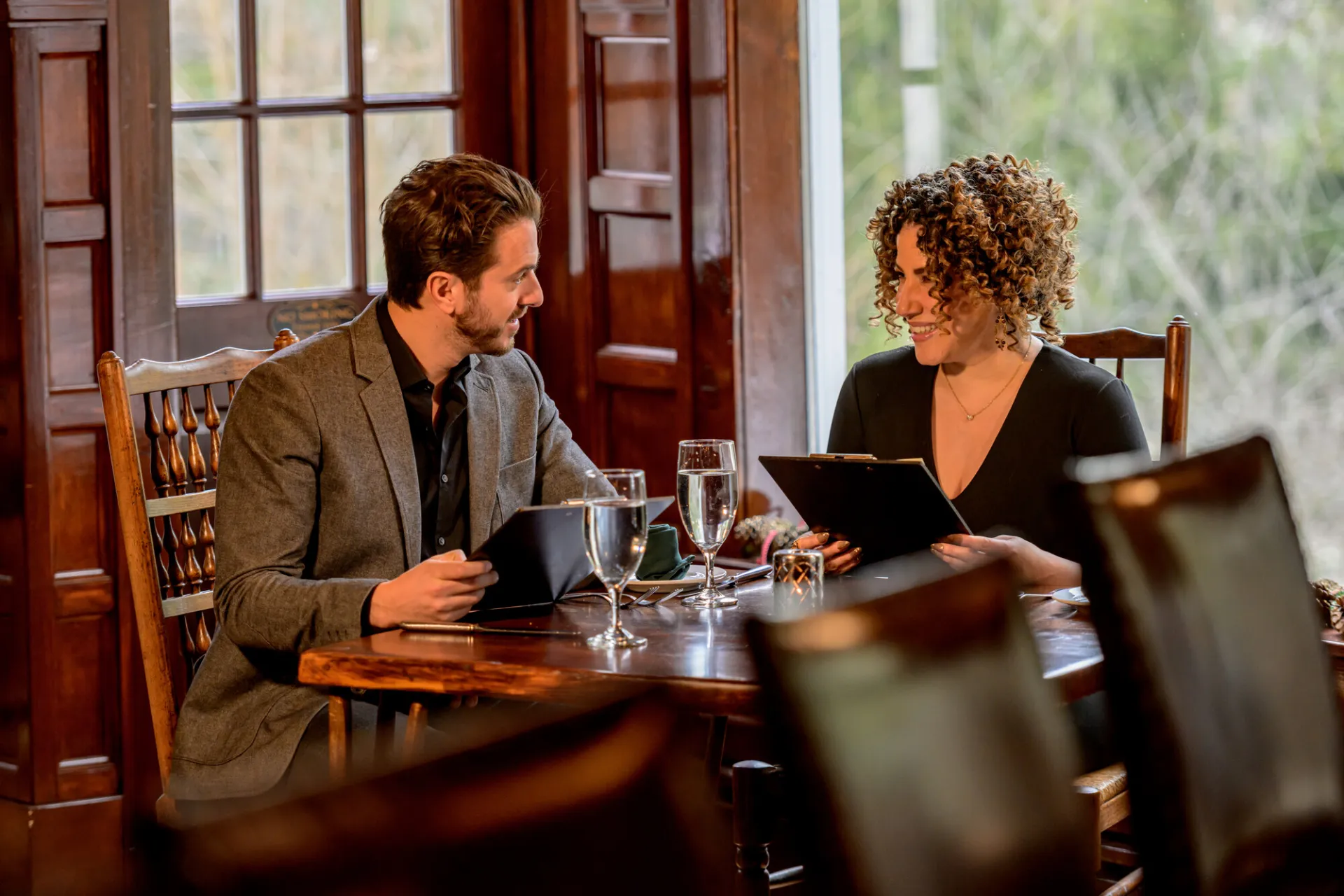 A man and woman sit down for a high end meal. 