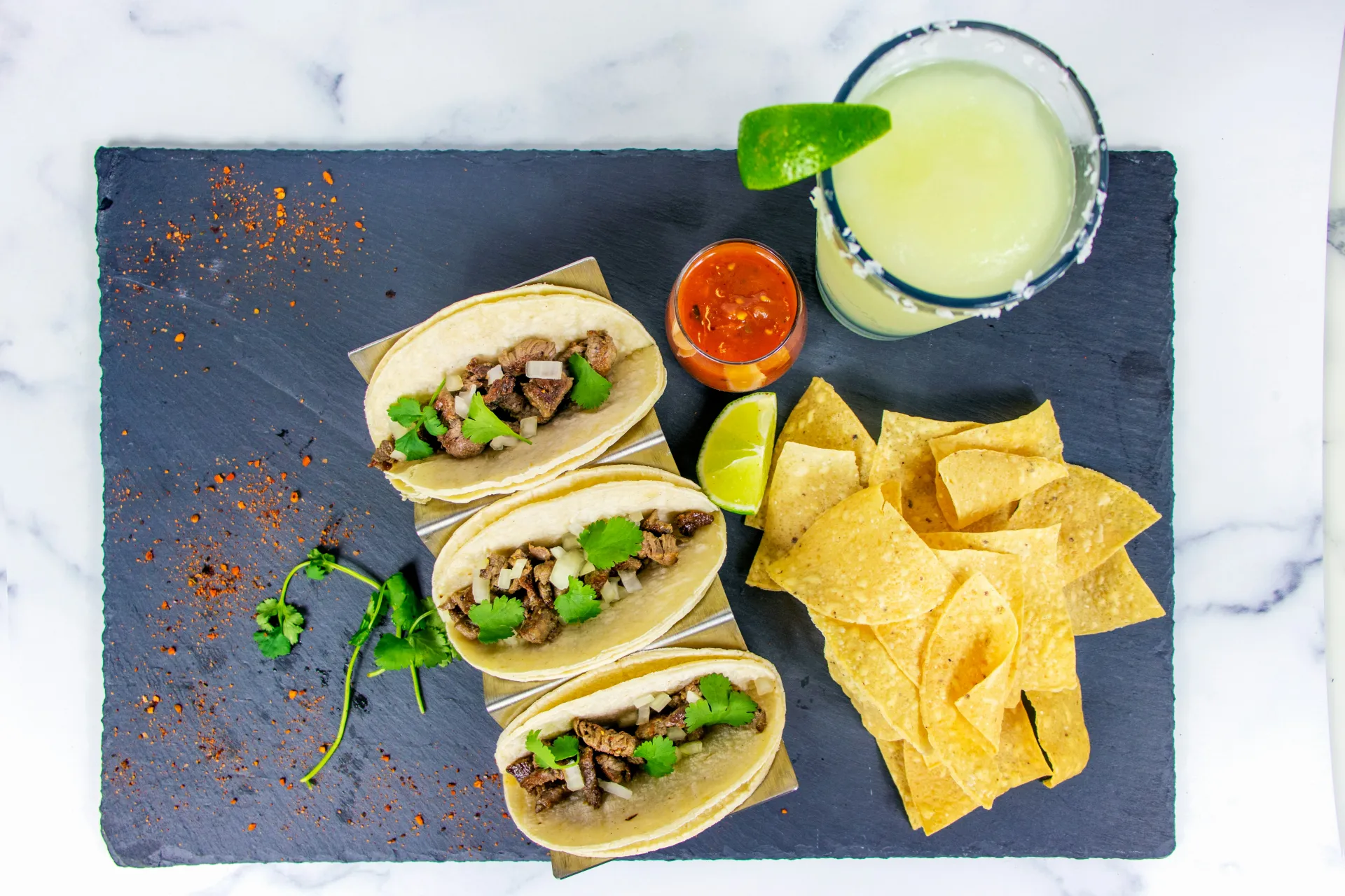 Overhead view of slate board holding tacos and margarita