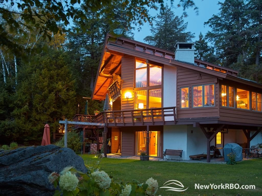 A large and warmly illuminated log cabin in the woods.