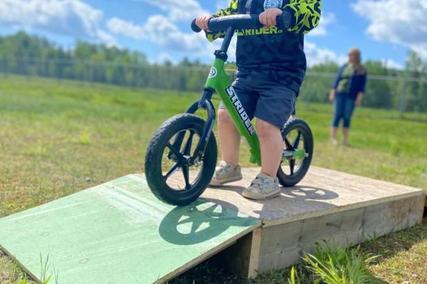 Young child on a balance bike from shoulder down. Bike is on a small ramp. 