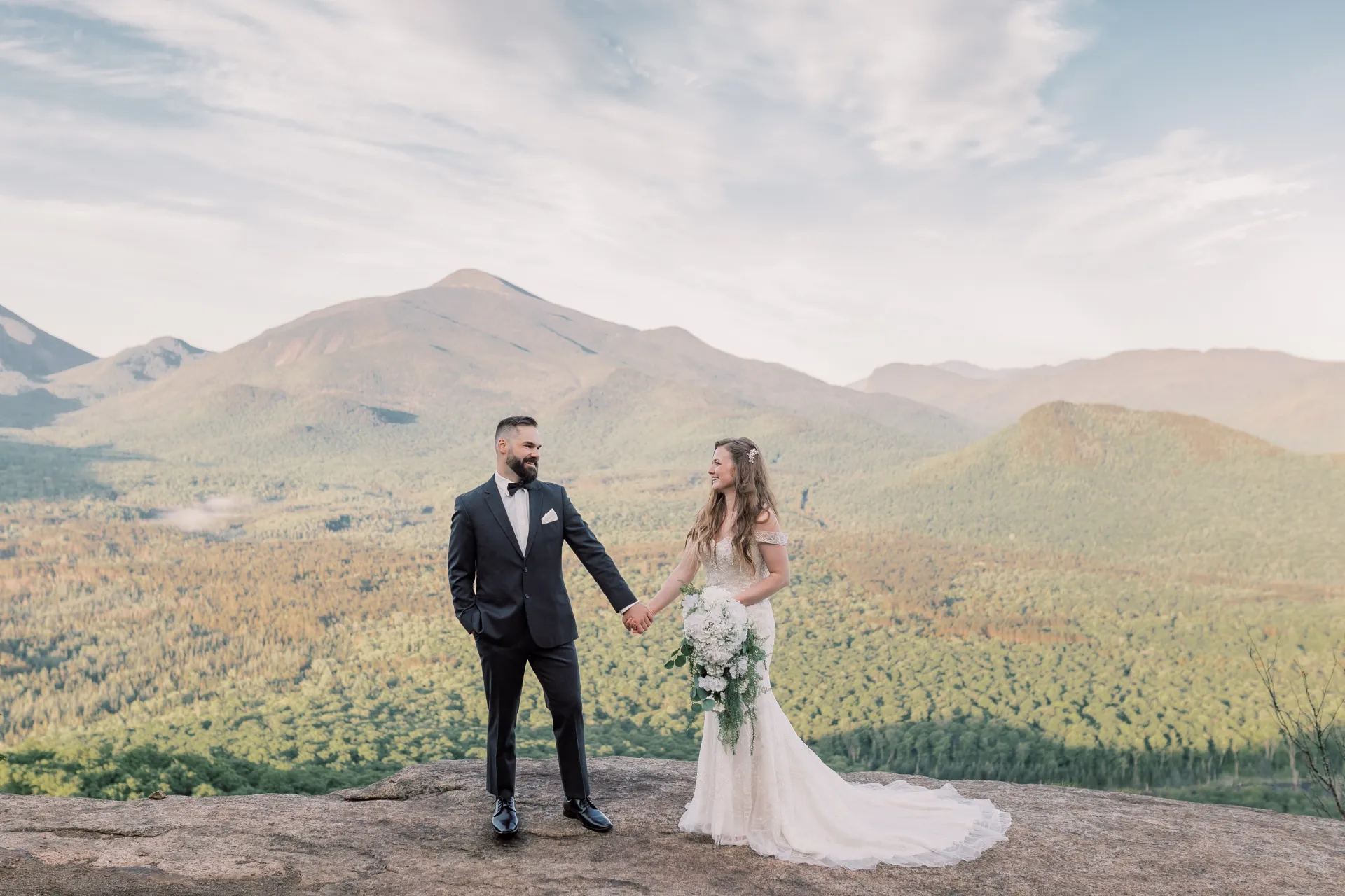 Bride and Groom gaze at each other while holding hands with mountain views in the background