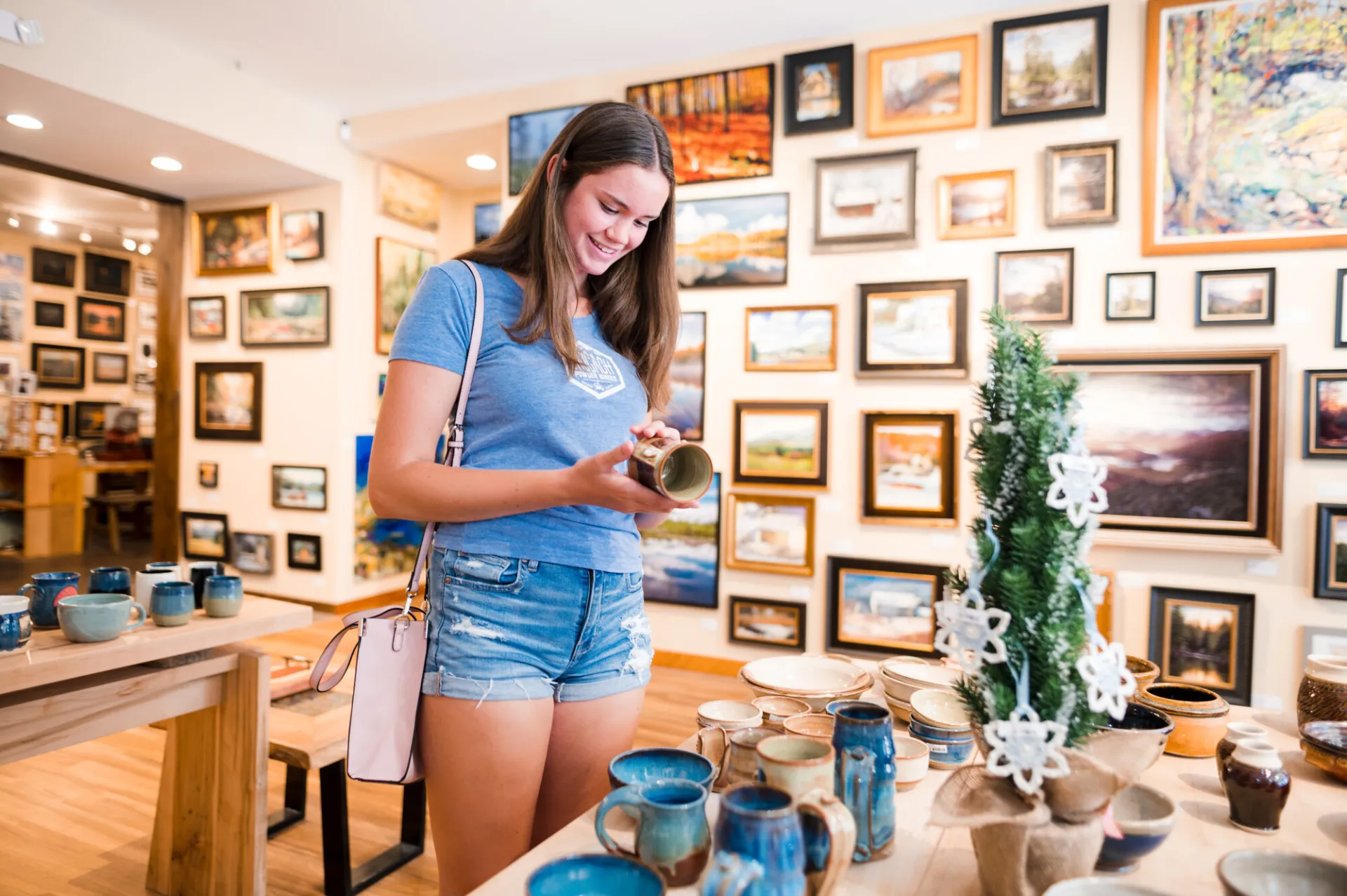 A young woman picks up a handmade mug at an art gallery.