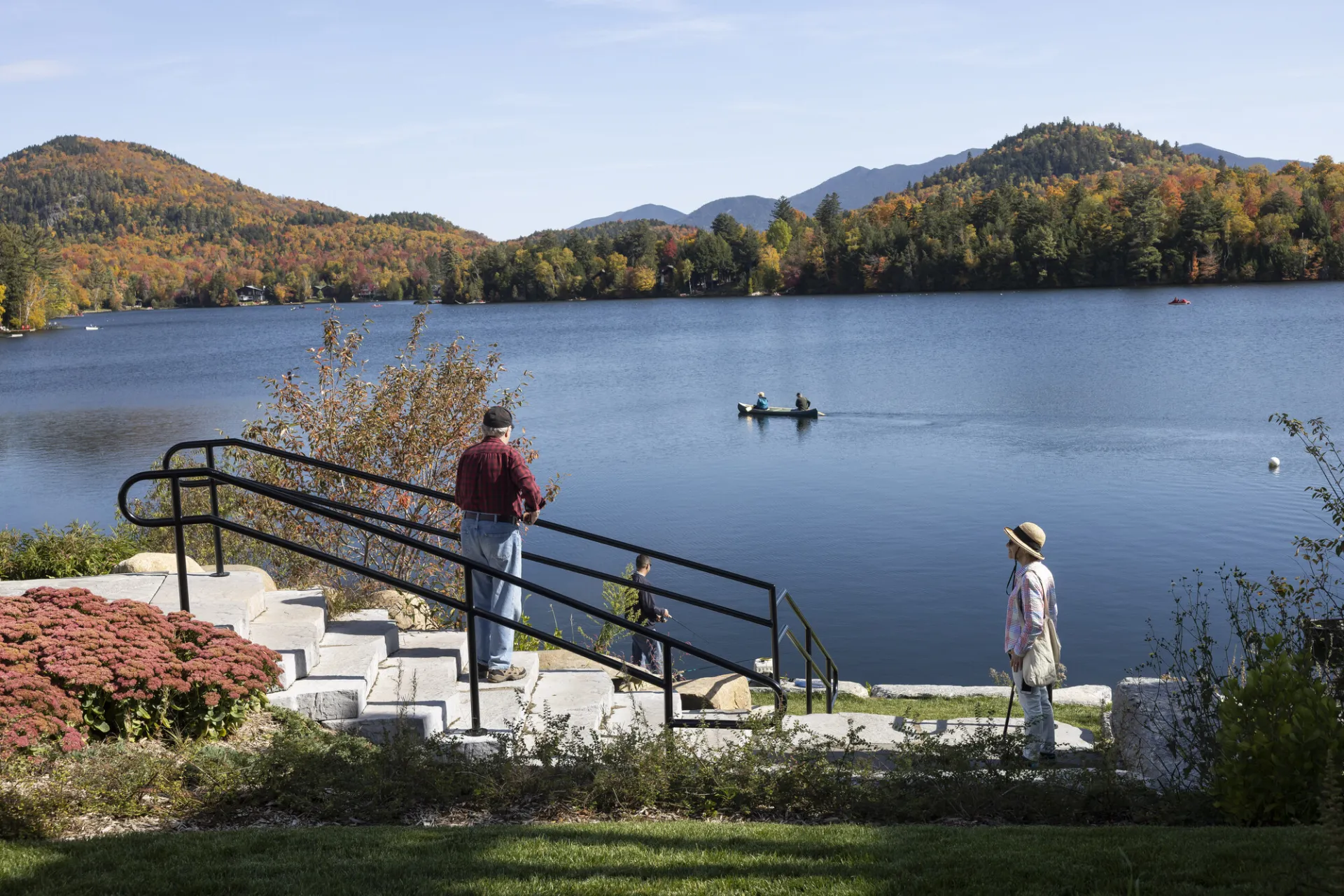 Two people watch a paddler out on a lake
