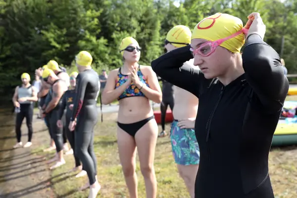 People stand ready to swim with their swim caps and goggles.