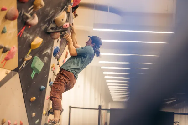 Climber ascends bouldering wall in indoor climbing gym