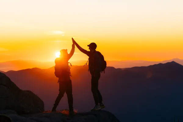 Two people high fiving on a summit