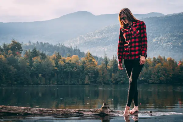 A woman walks on a log in a pond