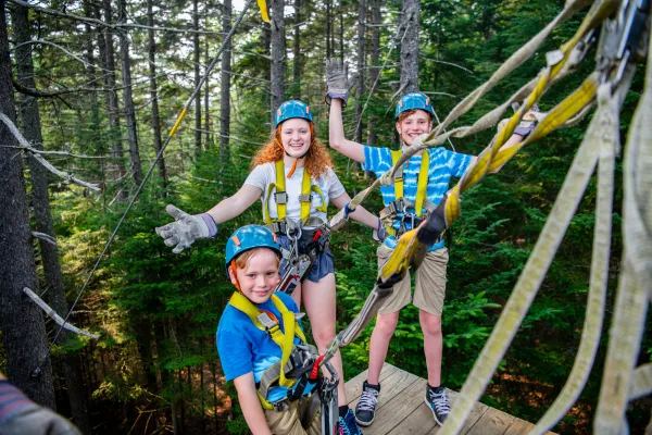 Three kids explore a zipline course. 