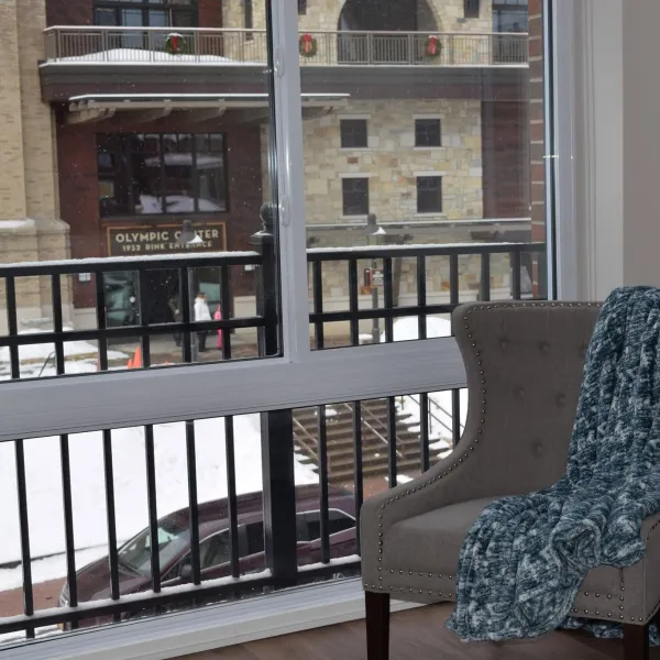 A chair with throw blanket looking out a large window at the Olympic Conference Center in the winter.