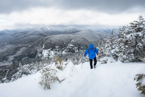A man walks up a snowy mountain trail
