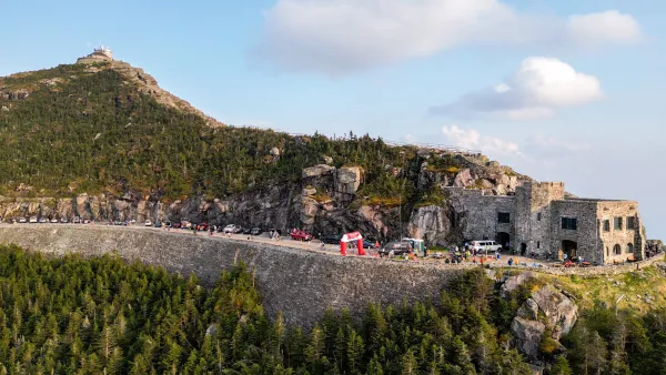 An aerial view displays a stone castle and a race finish arch with people along the road leading up to Whiteface Mountain.