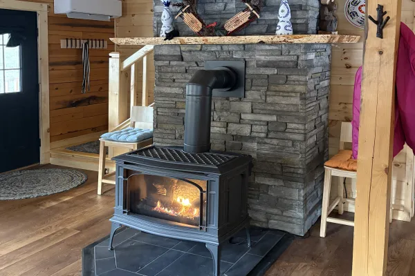 A fire burning in the wood stove in the stacked stone fireplace.