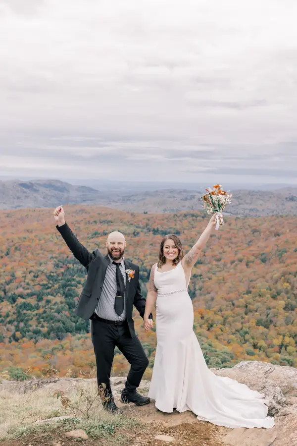 Bride and Groom rejoice and wave arms, smiling at the camera
