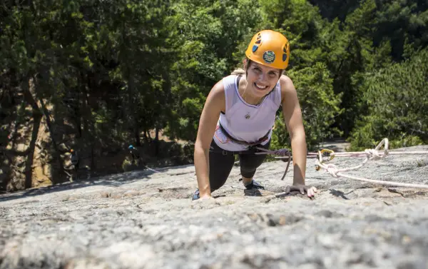 A climber posing for a photo on a cliff