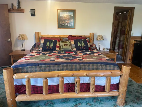 A king sized log bed with colorful quilts at Wildwood on the Lake.