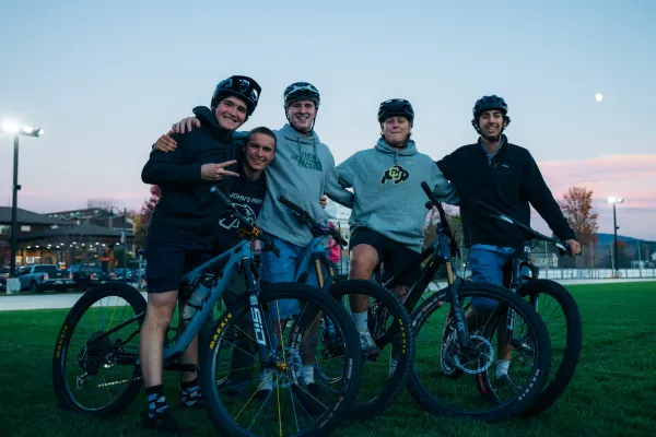 Group of five young men with bikes and helmets pose for group picture