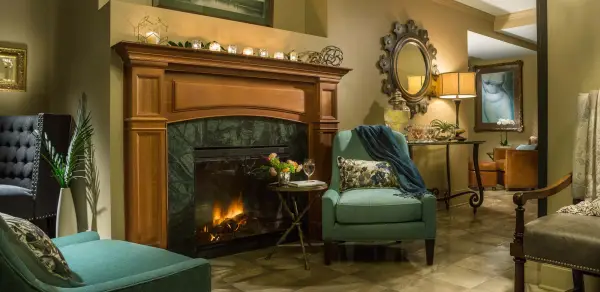 The luxurious women's lounge decorated with a robust fireplace, comfortable chairs, and candle light.
