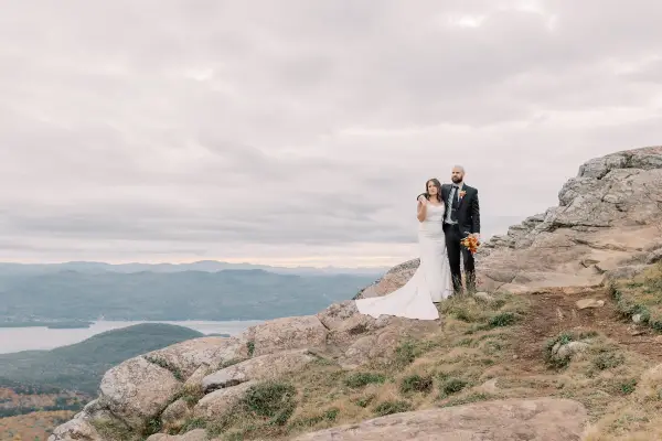 Bride and groom side hug on a rocky face overlooking the water