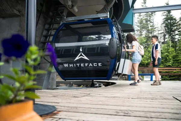 Two women board Whiteface Mountain gondola on summer day