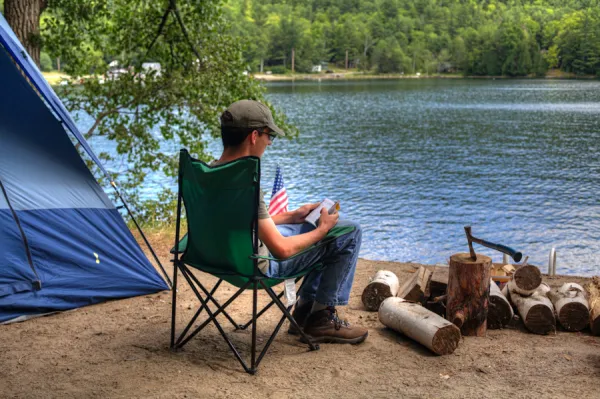 A person sitting in a camp chair by the water.