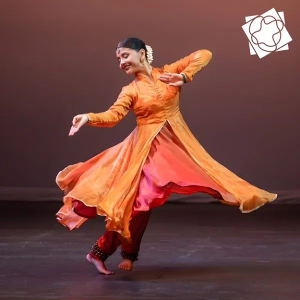Woman performs kathak dance on stage in traditional Indian clothing