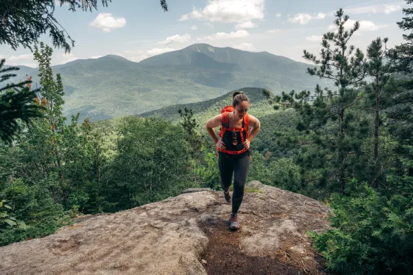 A woman climbs a rocky mountain top. 