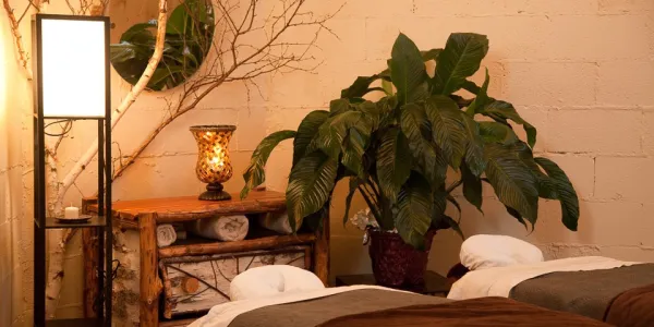 The couples massage room with two tables, a large plant and warm lighting at Healing Elements.