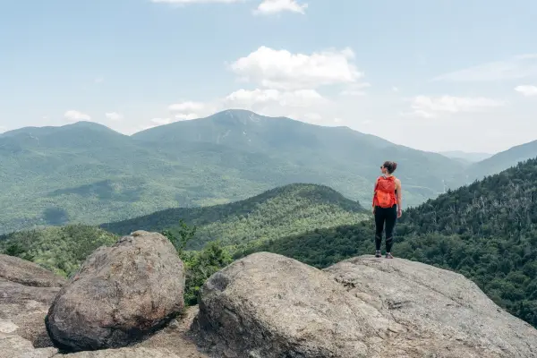 Hiker with red backpack at Rooster Comb summit