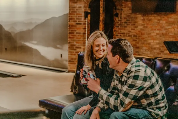 A happy couple enjoy a beverage by the bowling lanes.  Photo Credit to A. Kelly.