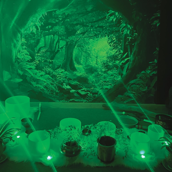 Forest background behind table holding candles and crystal bowls in dark green light