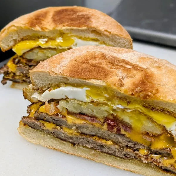 A cross-section cut of double smashburger topped with pickles and fried egg.