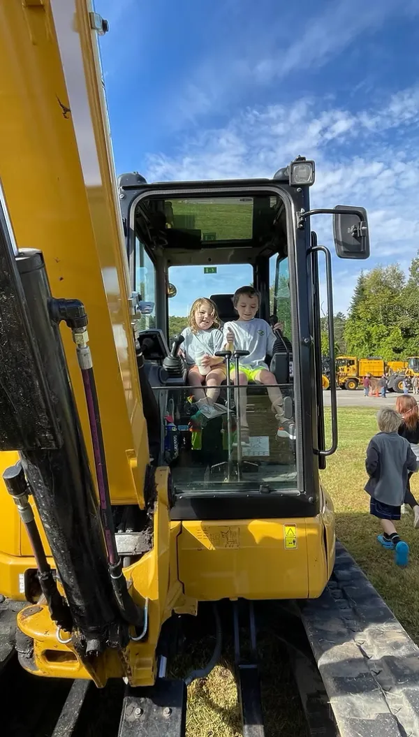 children sitting on yellow heavy machine