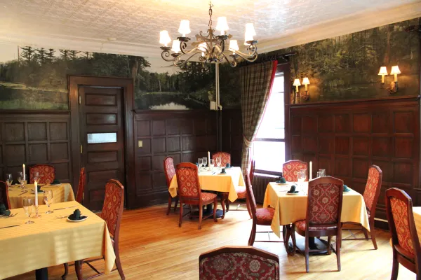 Dining room with white table clothes and dark paneled walls.