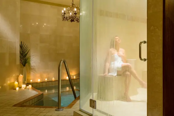A woman sits wrapped in a lush towel while basking in the rejuvenating steam room.