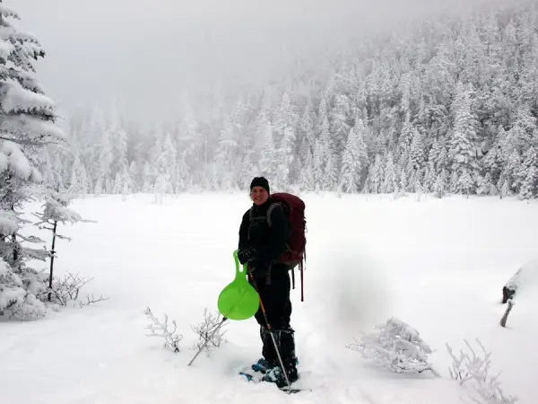 A hiker standing by a frozen pond