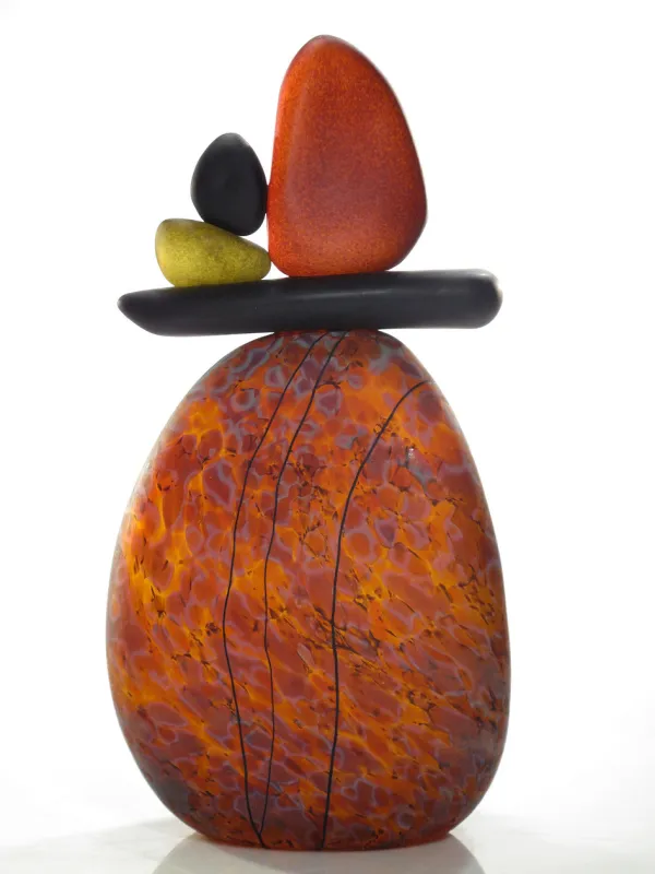 Larger orange rock balances flat black rock which then balances three more rocks