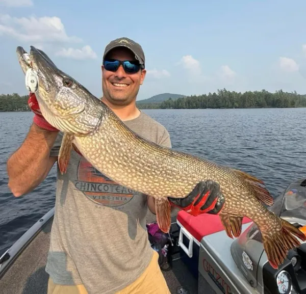 A smiling man holds a huge pike