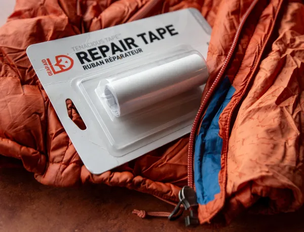 Package of repair tape sitting atop on orange technical wear jacket