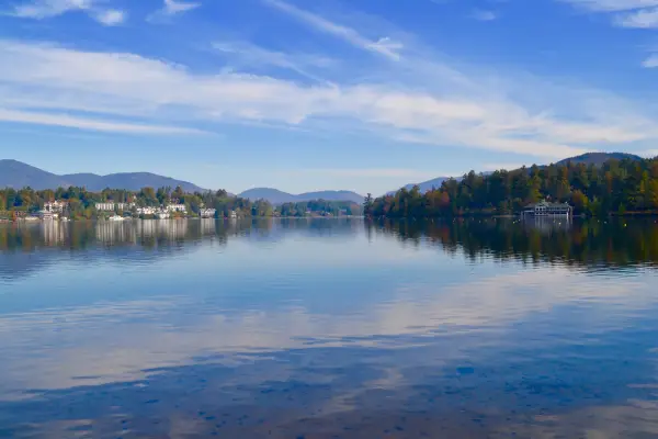 A lake reflects the partly-cloudy sky.