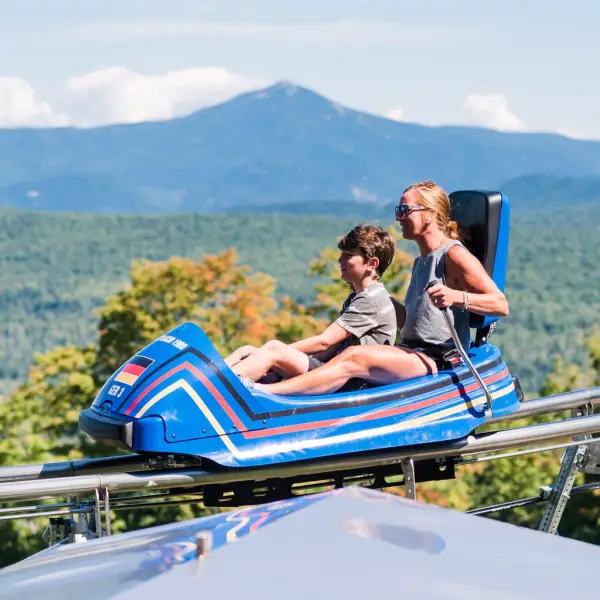 A woman and her young son ride a mountain coaster. 