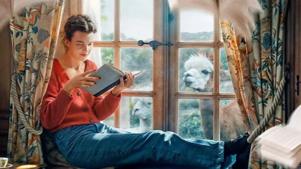Young woman from movie "Jane Austen Wrecked My Life" sits in a sunny window reading a book.